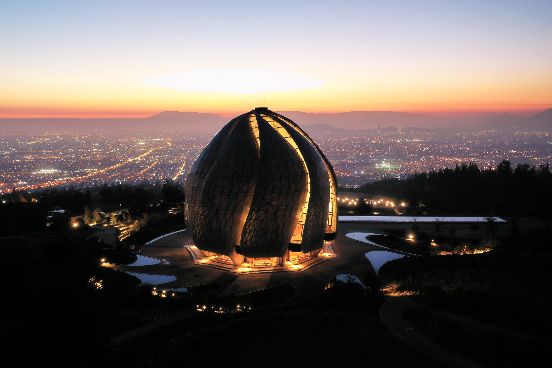 El Templo Bahá’í iluminado de noche reflejado en el espejo de agua