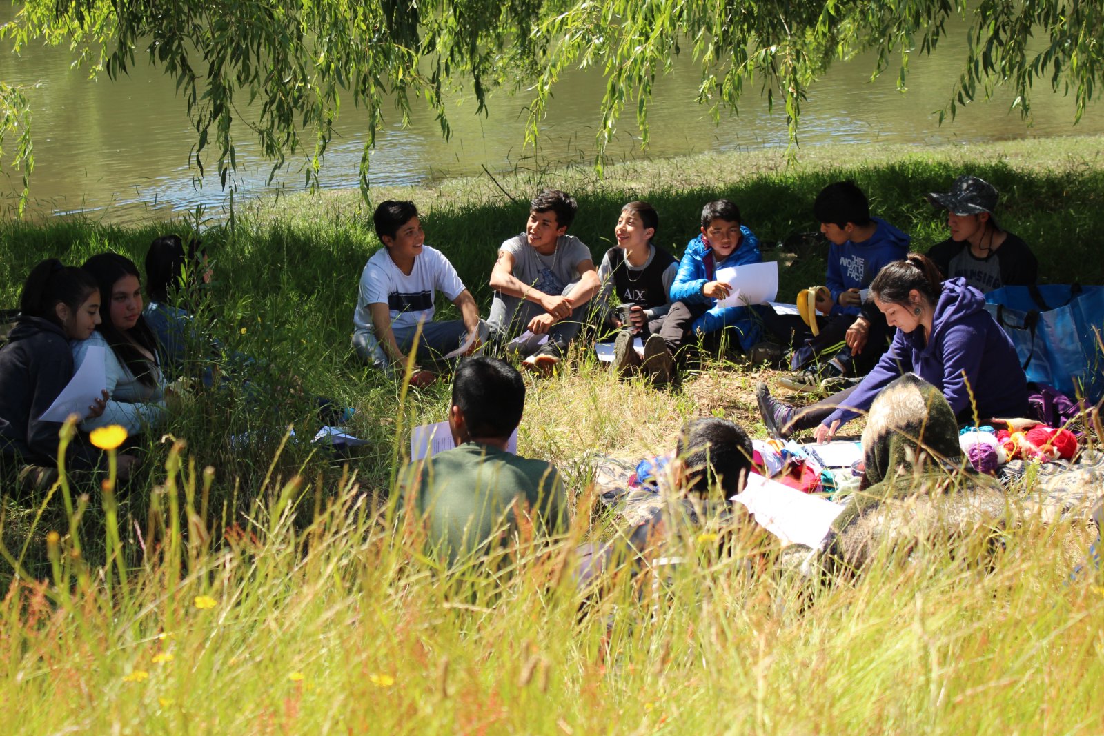 Jóvenes en un círculo de estudio al aire libre, junto a un río