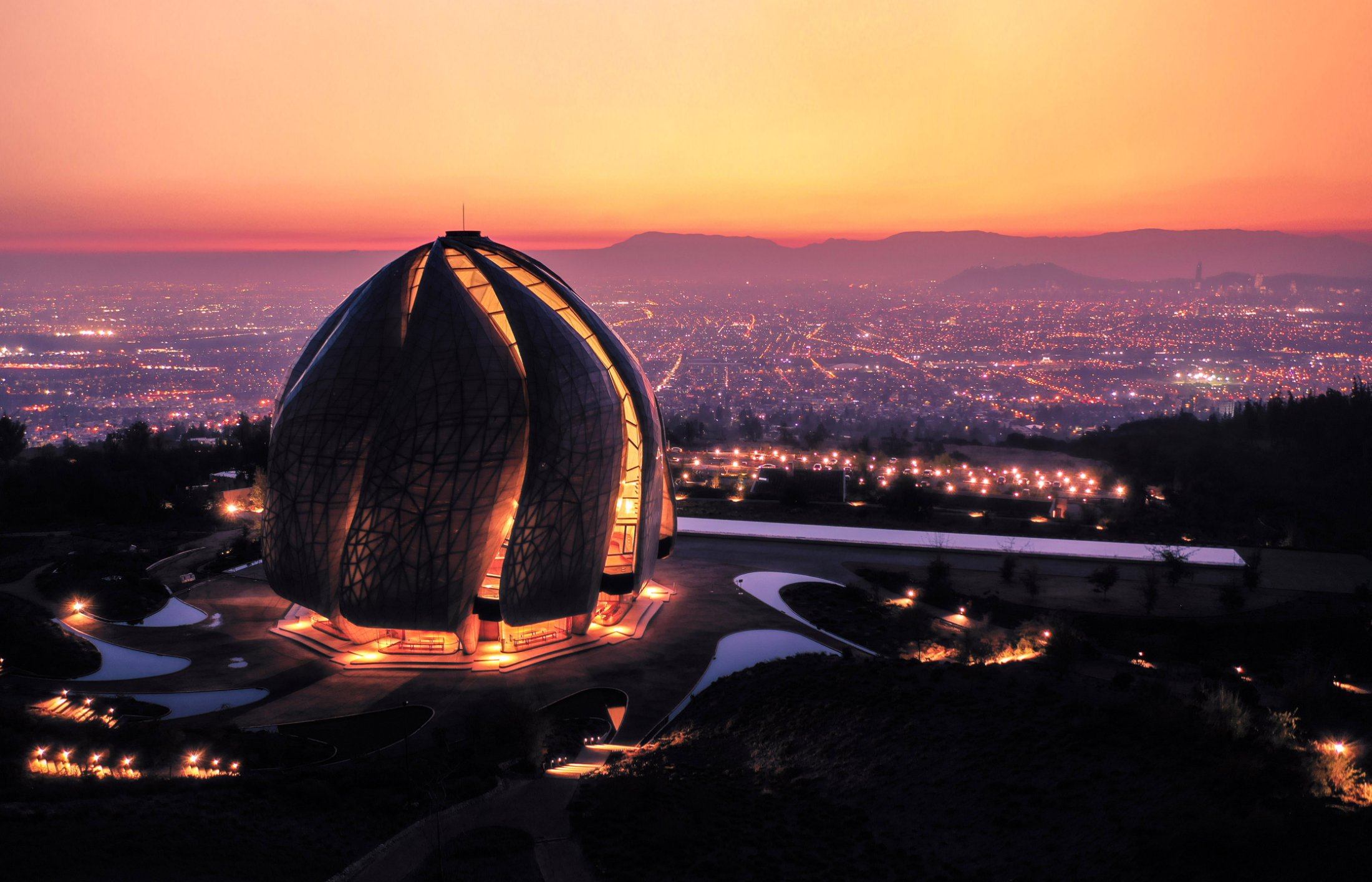 El Templo Bahá’í iluminado al atardecer sobre las luces de Santiago